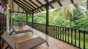 A covered outdoor area with a wooden ceiling, a black railing, and a view of lush greenery. - Villa Lima – Relaxing 2-Bedroom Oasis in Hacienda Pinilla (Hacienda Pinilla)