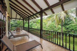 A covered outdoor area with a wooden ceiling, a black railing, and a view of lush greenery. - Villa Lima – Relaxing 2-Bedroom Oasis in Hacienda Pinilla (Hacienda Pinilla)