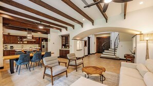 A spacious living area with a dining table, chairs, sofas, and a staircase leading to an upper level. - Villa Lima – Relaxing 2-Bedroom Oasis in Hacienda Pinilla (Hacienda Pinilla)