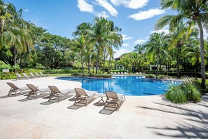 A swimming pool with lounge chairs and palm trees. - Villa Lima – Relaxing 2-Bedroom Oasis in Hacienda Pinilla (Hacienda Pinilla)