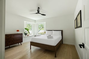 A bedroom with a bed, dresser, windows, and a ceiling fan. - Travis Height/SoCo - 60s Charm, Modern Soul (Austin)