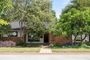 A residential house with a front porch, a brick facade, and a lawn.