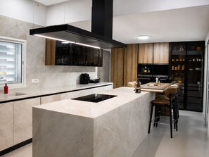 A modern kitchen with a central island, black cabinetry, and a built-in oven. - Premium Villa with Pool and Large Garden S 15 (Tunis)