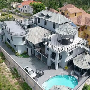 A multi-story residential building with a swimming pool, balconies, and a garage. - Luxury 9 Bedroom Villa, Ironshore Montego Bay (Montego Bay)