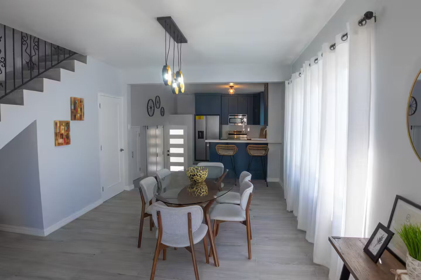 A dining area with a round table, chairs, and a staircase.