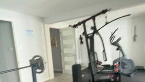 Une salle de sport équipée d’un banc de développé couché, d’un support à poids et de divers appareils d’exercice.