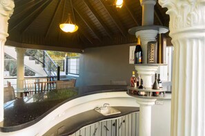 A modern bar area with a curved countertop, a wine rack with bottles, and a staircase leading to an outdoor area. - 3 Bedrooms, Ironshore Montego Bay (Montego Bay)