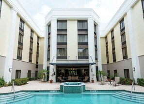 A hotel with a pool, outdoor seating, and a covered entrance. - Convenient Base for Exploring Local Charm | Free Breakfast and Parking (Boca Raton)