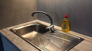 A modern kitchen with a stainless steel sink, wooden countertop, and a bottle of dish soap.