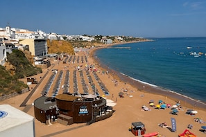 Une plage bordée de rangées de transats, un bâtiment en bois portant l’inscription « ROCA », et une vue dégagée sur la mer.