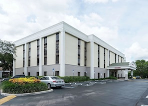 A large building with a flat roof, multiple windows, and a parking lot with marked spaces. - Affordable Unit w/ Breakfast | Quiet & Comfortable Location for Travelers (Boca Raton)