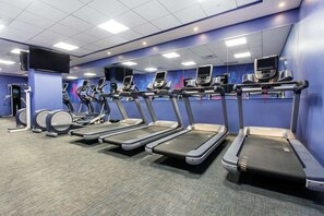 Ein Fitnessstudio mit Laufbändern, Crosstrainern und einem Ergometer.