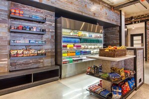 Eine Snackbar mit Regalen voller Snacks, abgefüllten Getränken und einer Auswahl an Obst und Gemüse.