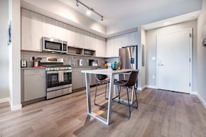 A modern kitchen with a central island, stainless steel appliances, and a white door. - Waterfront Luxury Living in Harbor Point (Stamford, CT)