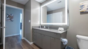 Une salle de bain moderne avec un meuble-lavabo gris, un grand miroir et des toilettes.