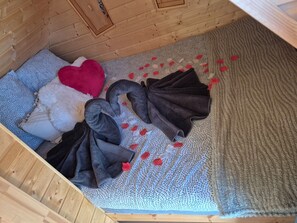 A wooden room with a bed, pillows, and a blanket. - Vrbo Property (Rahon)