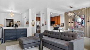 A modern living room with a sectional sofa, a small side table, and a dining area with a white table and chairs. - Welcome to Baby Mars: The Ultimate Waterfront Base (Seattle)
