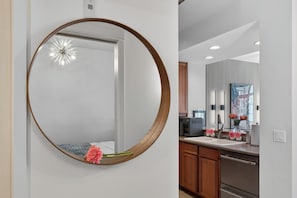 A modern kitchen with a large round mirror, wooden cabinets, and a stainless steel refrigerator. - Welcome to Baby Mars: The Ultimate Waterfront Base (Seattle)