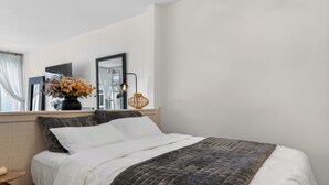 A bedroom with a bed, a nightstand, a mirror, a vase with flowers, and a lamp. - Welcome to Baby Mars: The Ultimate Waterfront Base (Seattle)