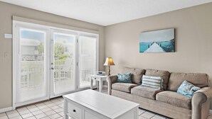 Un salon avec un canapé beige, une table basse blanche et un tableau accroché au mur.