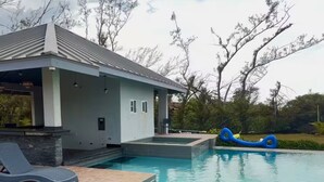 Une piscine avec un fauteuil de relaxation et un petit bâtiment en arrière-plan.
