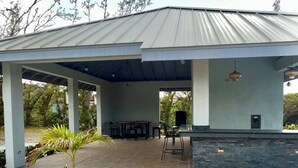 Un espace extérieur abrité, doté d’un sol en pierre, d’un barbecue et d’un coin salon.