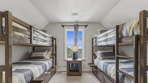 A room with two bunk beds, a window with curtains, a small table with a lamp, and a ceiling vent. - Brand new home - The Homestead (Columbus)