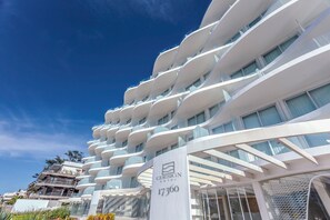 Ein modernes Hotel mit einer markanten, geschwungenen Fassade, mehreren Balkonen und blauem Himmel.
