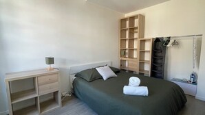Quarto com cama, escrivaninha, guarda-roupa e cabideiro.