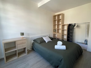 A bedroom with a bed, a desk, a wardrobe, and a hanging clothes rack. - Apartment on Hugues Street (Bayonne)
