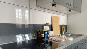 Cozinha moderna com bancada preta, eletrodomésticos de aço inoxidável e tábua de corte de madeira.