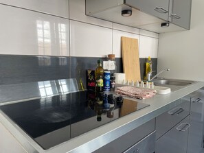 A modern kitchen with a black countertop, stainless steel appliances, and a wooden cutting board. - Apartment on Hugues Street (Bayonne)