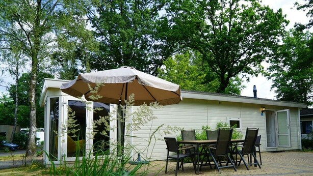 A patio with a table and chairs, an umbrella, and a building with a door and windows. - Holiday Home in Arnhem With Terrace (Arnhem)