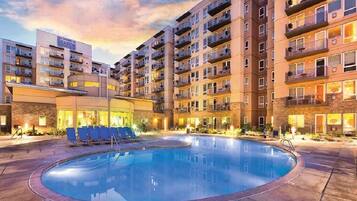 Un hôtel doté d’une piscine, de plusieurs balcons et d’une façade bien éclairée.