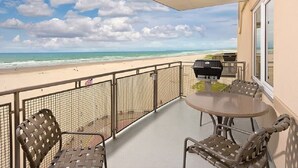 Ein Balkon mit Blick auf den Strand, einem Grill und Sitzgelegenheiten im Freien.
