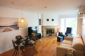 Ein modernes Wohnzimmer mit Fernseher, Kamin, Essbereich und Sitzgelegenheiten.