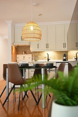 A modern kitchen with white cabinets, a central island, and a hanging light fixture. - O` Bord du Lac Memphrémagog (Magog)