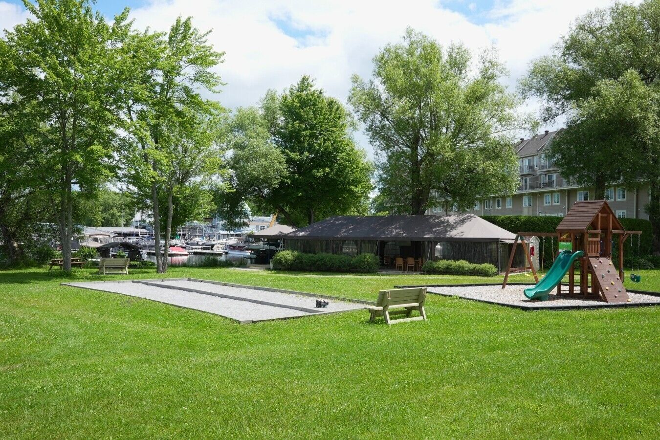 A park with a playground, picnic tables, and a building in the background.