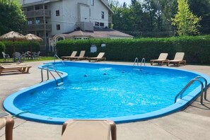 A swimming pool with lounge chairs and a building in the background. - O` Bord du Lac Memphrémagog (Magog)