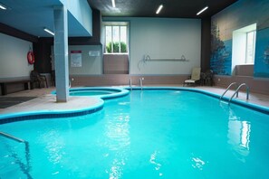 Ein Hallenbad mit klarem Wasser, einem Rettungsring und einem Wandgemälde.