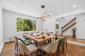 A dining area with a wooden table, chairs, and a modern pendant light.