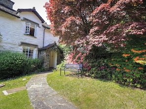 A stone pathway leading to a traditional stone building with a garden.