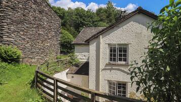 A stone wall, a white building with two windows, and a wooden fence.