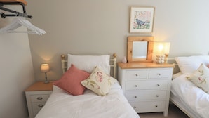 Une chambre à coucher comprenant un lit, une table de chevet, une commode, un miroir et une étagère fixée au mur.