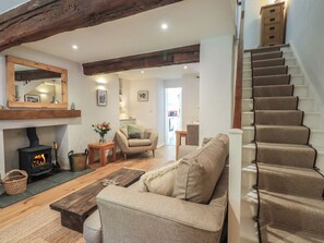 A cozy living room with a fireplace, a sofa, a wooden coffee table, and a staircase.