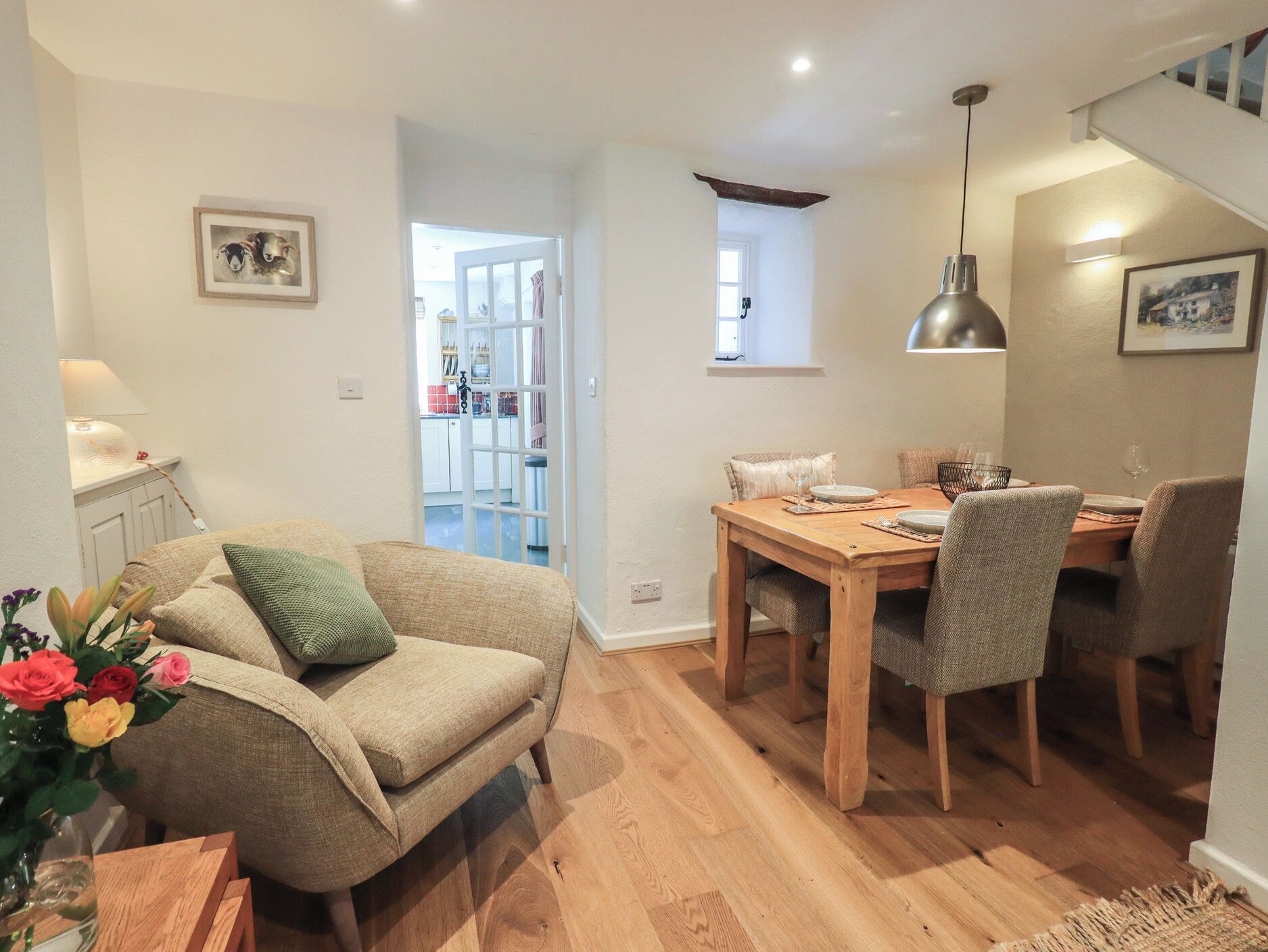 Una sala de estar acogedora con sofá, una mesa de comedor con sillas, una cocina al fondo y una escalera.