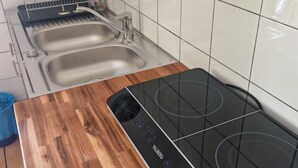 A kitchen with a wooden countertop, a black induction cooktop, and two stainless steel sinks. - A 35-square-meter studio in the heart of downtown, just a stone's throw from all the attractions. (Béziers)