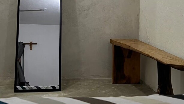 A room with a wooden bench, a mirror, and a door. - Located in the heart of Zicatela (Brisas de Zicatela)