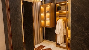 A modern bathroom with dark marble walls, a wooden vanity, and a robe rack. - glow pyramid view (Giza)