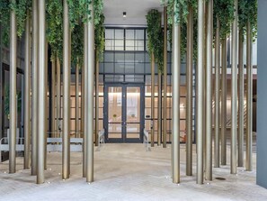 Eine moderne Lobby mit hohen Säulen, einem zentralen Eingang und Blick ins Innere des Gebäudes.
